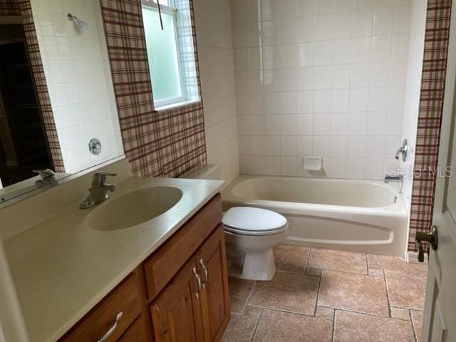 full bathroom featuring tiled shower / bath combo, vanity, and toilet