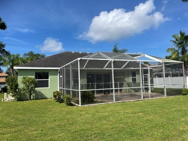 rear view of property with a patio, a lanai, and a lawn