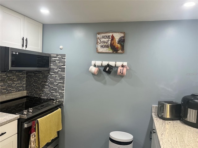 kitchen featuring white cabinets, electric range, tasteful backsplash, and light stone countertops