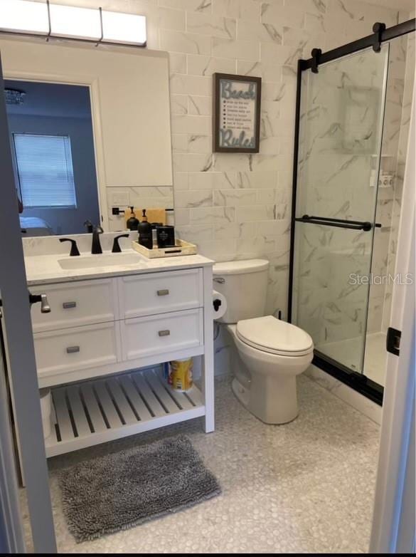 bathroom with a shower with door, vanity, and toilet