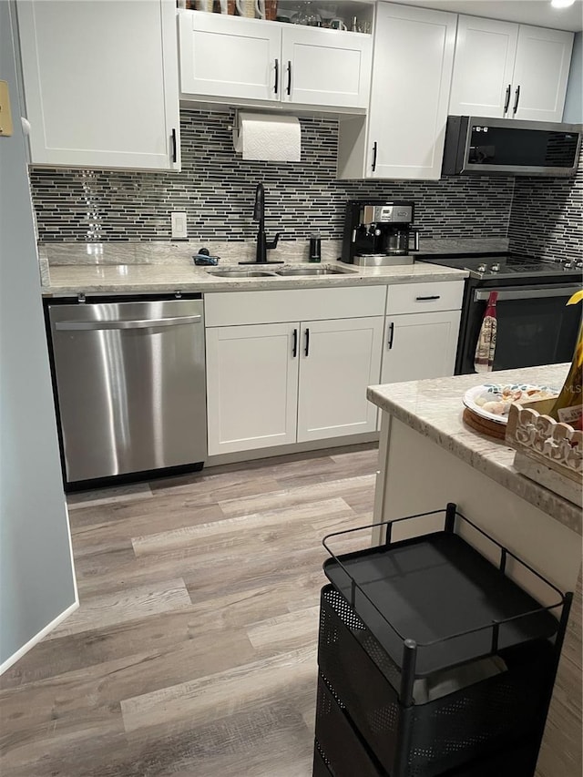 kitchen featuring appliances with stainless steel finishes, light hardwood / wood-style floors, white cabinetry, and sink