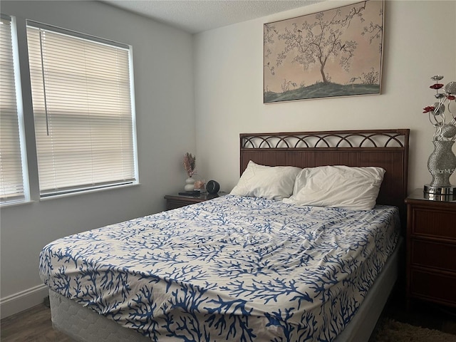 bedroom with multiple windows, dark wood-type flooring, and a textured ceiling