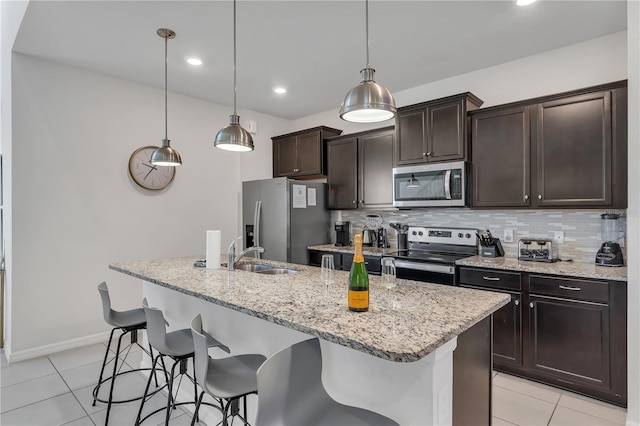 kitchen featuring dark brown cabinetry, stainless steel appliances, sink, pendant lighting, and a center island with sink