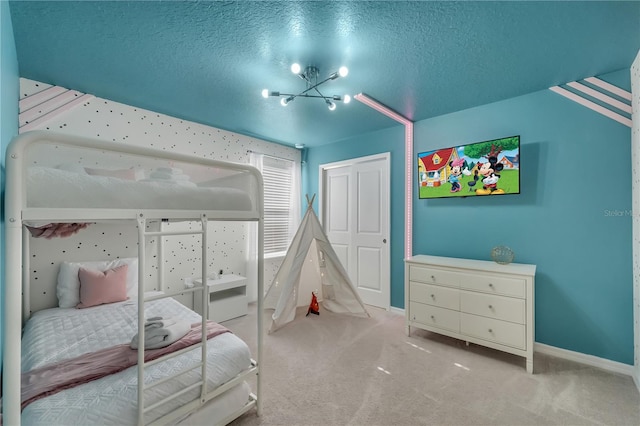 carpeted bedroom with a notable chandelier, a textured ceiling, and a closet