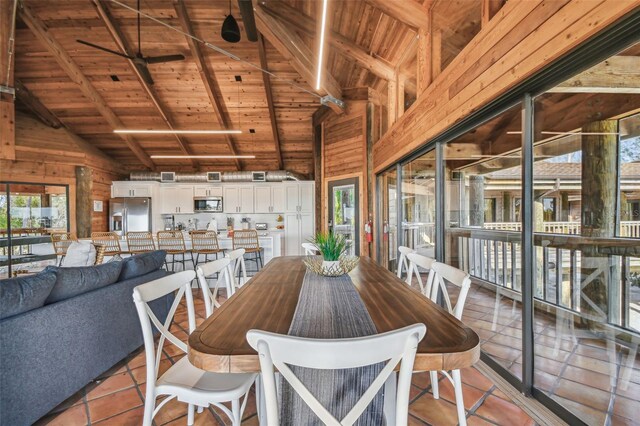 dining room featuring beamed ceiling, wood ceiling, wooden walls, and light tile patterned flooring