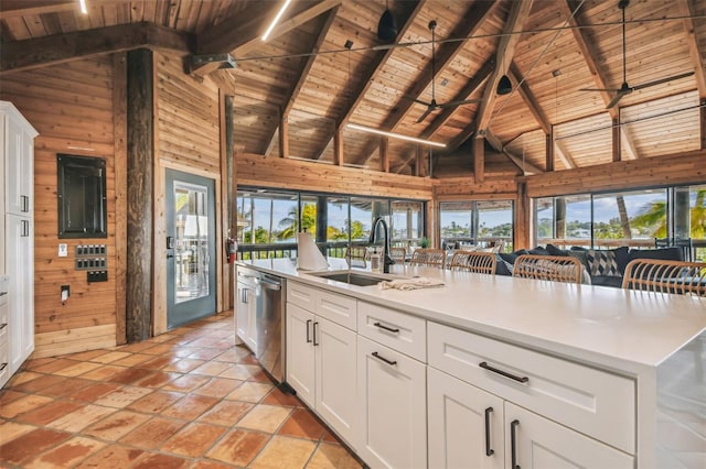 kitchen with wood walls, plenty of natural light, high vaulted ceiling, and sink