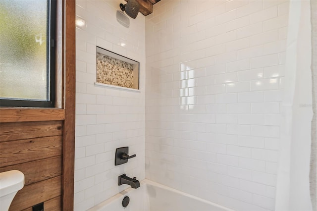 bathroom featuring tiled shower / bath combo and toilet