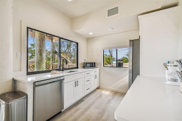 kitchen with sink, white cabinets, light hardwood / wood-style floors, and appliances with stainless steel finishes