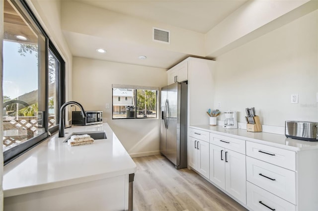 kitchen with white cabinetry, light wood-type flooring, stainless steel fridge with ice dispenser, and sink