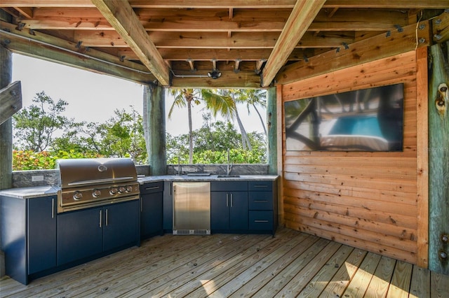 wooden terrace with sink, area for grilling, and a grill