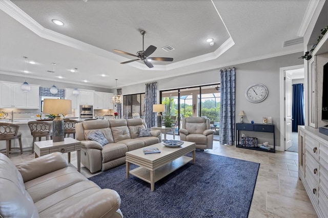 living room with a textured ceiling, a raised ceiling, ceiling fan, and crown molding