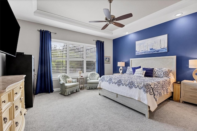 carpeted bedroom with a raised ceiling and ceiling fan