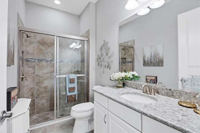 bathroom with tile patterned floors, vanity, a shower with shower door, and toilet