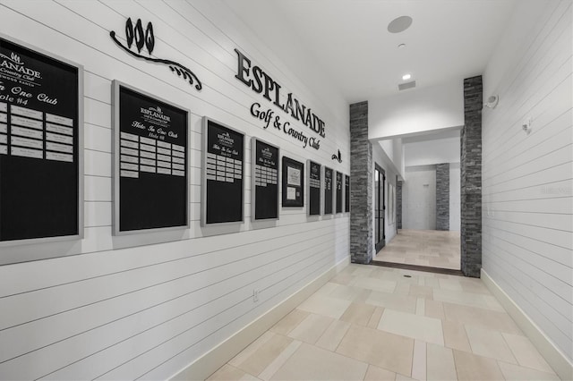 corridor with tile patterned flooring and wood walls