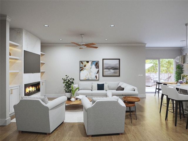 living room featuring ceiling fan, crown molding, hardwood / wood-style flooring, built in features, and a fireplace