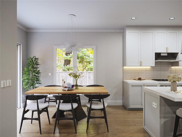 dining area featuring wood-type flooring, crown molding, and a chandelier