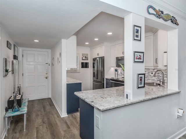 kitchen featuring sink, kitchen peninsula, decorative backsplash, stainless steel fridge, and white cabinetry