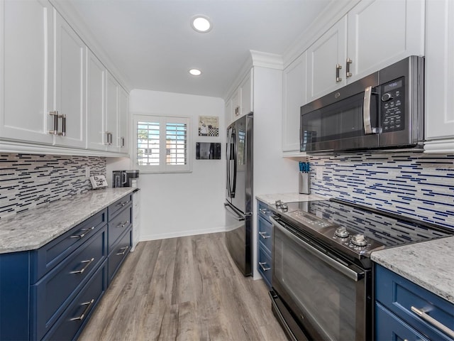 kitchen with stainless steel appliances, blue cabinets, light hardwood / wood-style floors, decorative backsplash, and white cabinets