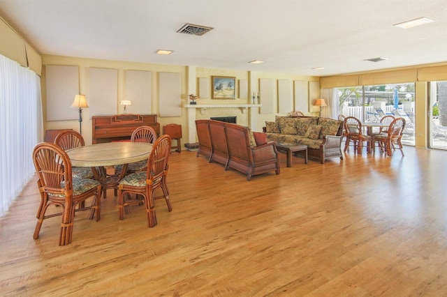 dining room with a fireplace, visible vents, and light wood-type flooring