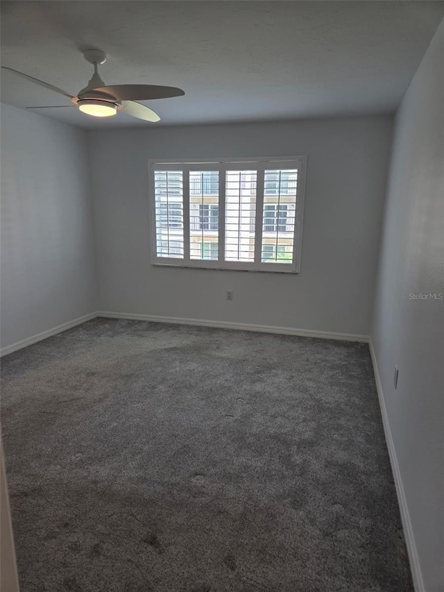 carpeted spare room with a ceiling fan and baseboards