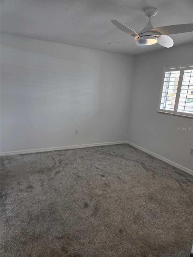 carpeted empty room with a ceiling fan and baseboards