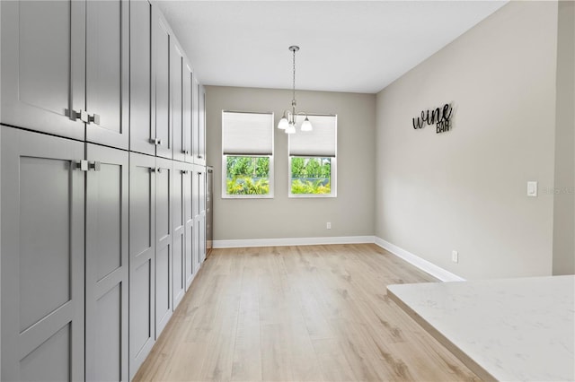 unfurnished dining area featuring a chandelier and light hardwood / wood-style flooring