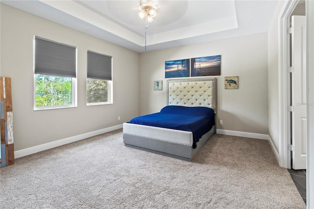 carpeted bedroom featuring ceiling fan and a raised ceiling