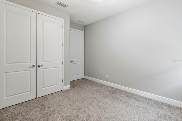 unfurnished bedroom with light carpet and a closet