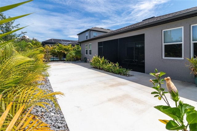 view of side of home with a patio area and a lanai