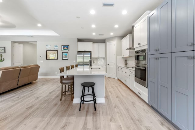 kitchen featuring a breakfast bar, sink, an island with sink, light hardwood / wood-style floors, and stainless steel appliances