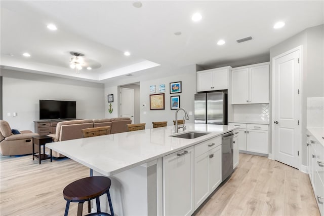 kitchen featuring white cabinets, appliances with stainless steel finishes, sink, and an island with sink