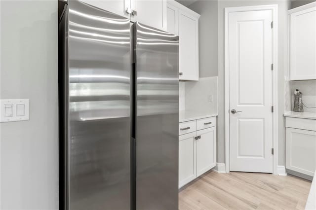 kitchen featuring tasteful backsplash, stainless steel refrigerator, white cabinets, and light hardwood / wood-style floors