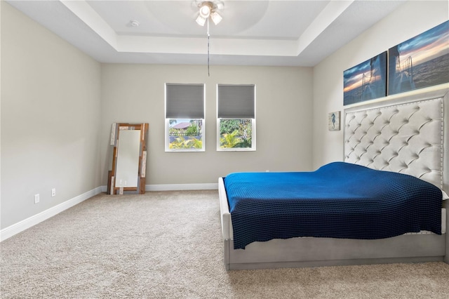 carpeted bedroom with ceiling fan and a tray ceiling