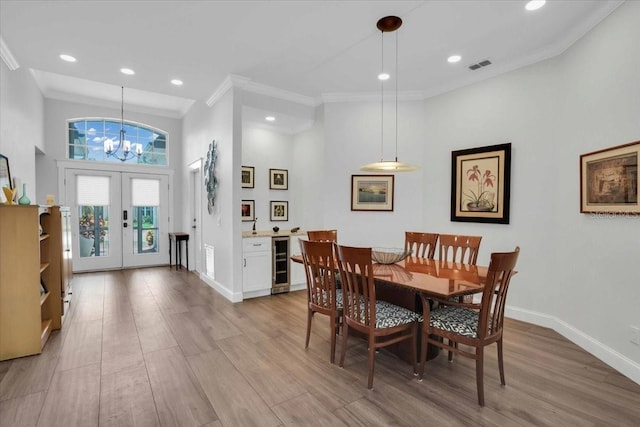 dining area with french doors, wine cooler, ornamental molding, a notable chandelier, and light wood-type flooring