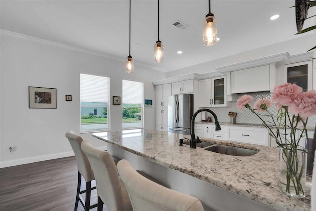 kitchen with sink, white cabinetry, hanging light fixtures, and stainless steel refrigerator