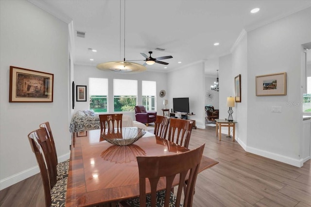 dining room with hardwood / wood-style flooring, ceiling fan with notable chandelier, and ornamental molding