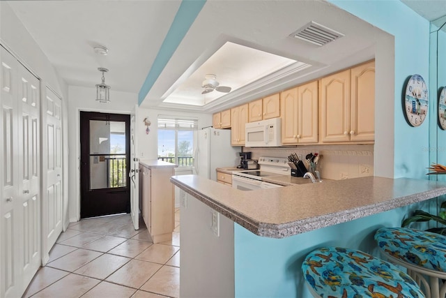 kitchen with ceiling fan, a raised ceiling, light brown cabinetry, kitchen peninsula, and white appliances