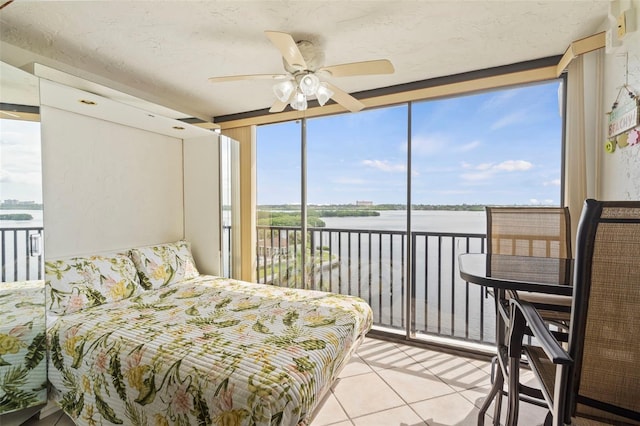 tiled bedroom featuring a wall of windows, ceiling fan, a textured ceiling, and access to exterior