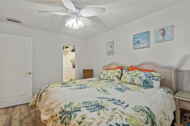 bedroom with ceiling fan, a closet, a spacious closet, and hardwood / wood-style floors