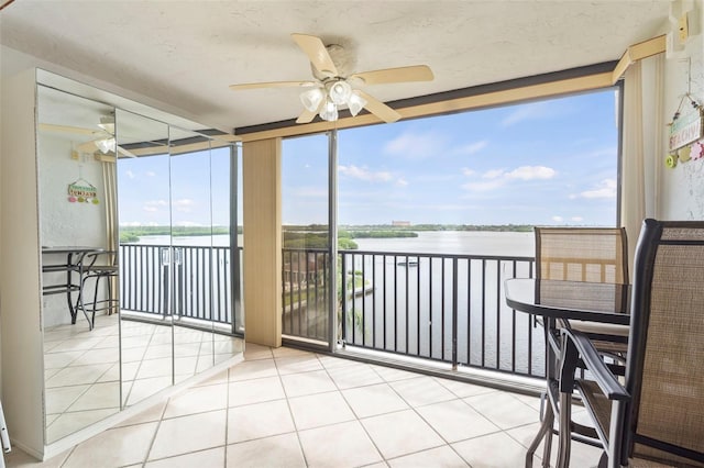 sunroom / solarium with ceiling fan and a water view