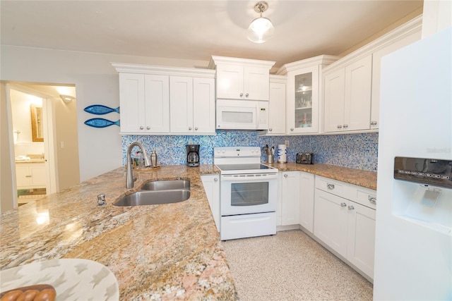 kitchen with white cabinets, light stone counters, white appliances, and sink