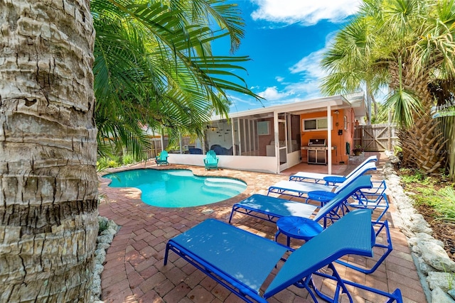 view of pool with a sunroom, area for grilling, and a patio area