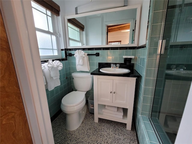 bathroom with tile walls, speckled floor, toilet, and a stall shower