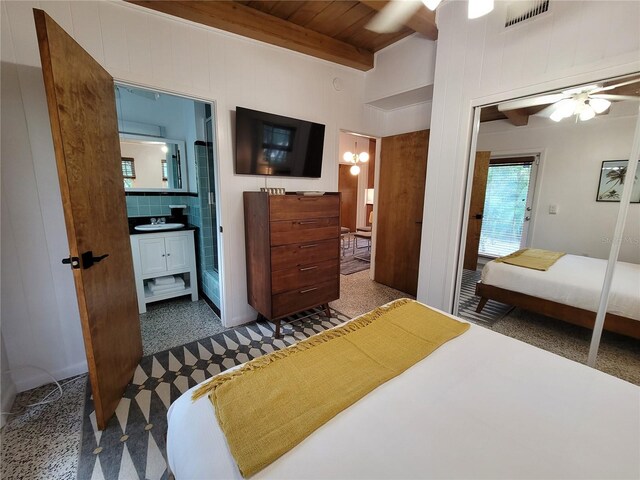 bedroom with visible vents, beam ceiling, a sink, ensuite bath, and wooden ceiling