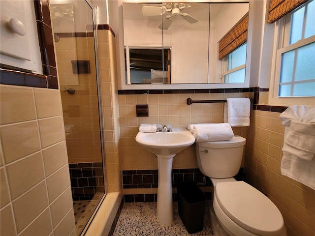 full bath featuring plenty of natural light, toilet, tile walls, and a shower stall