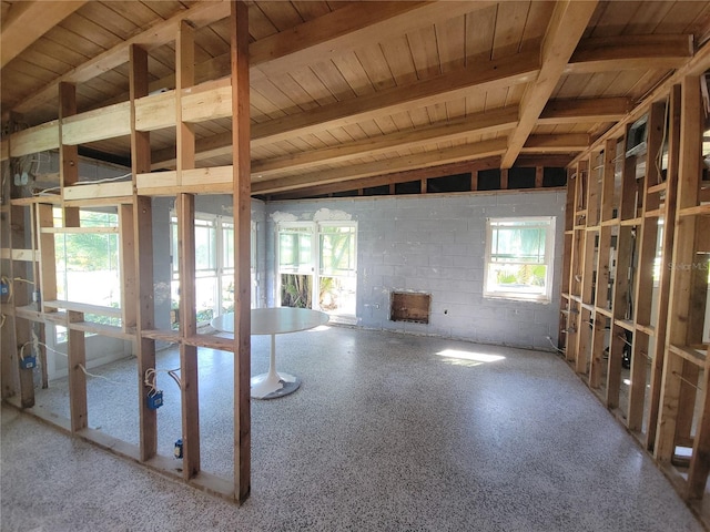 miscellaneous room featuring a wealth of natural light, beam ceiling, wooden ceiling, and concrete block wall