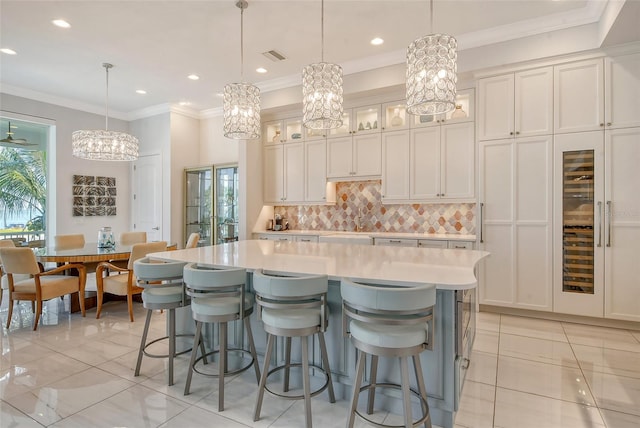 kitchen with white cabinetry, tasteful backsplash, crown molding, pendant lighting, and a spacious island