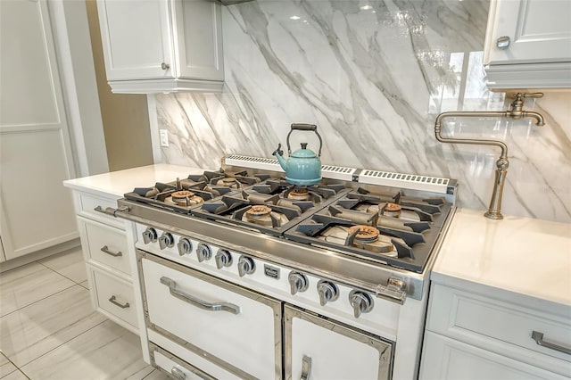 kitchen featuring white cabinets, light tile patterned floors, backsplash, and stovetop