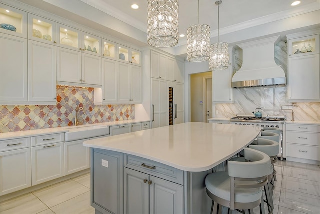 kitchen with a breakfast bar, backsplash, premium range hood, white cabinets, and a kitchen island