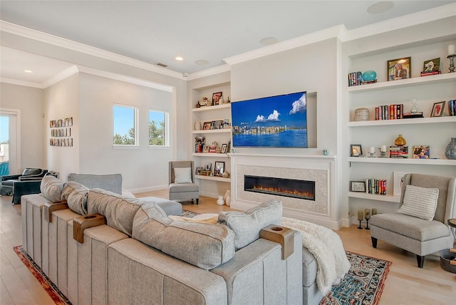 living room featuring built in shelves, ornamental molding, and light hardwood / wood-style flooring